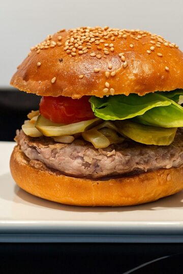 Hamburguesa casera gourmet con pan artesanal hecho en panificadora Silvercrest, servida en un plato blanco.