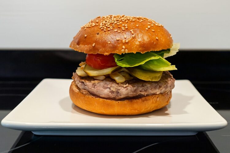 Hamburguesa casera gourmet con pan artesanal hecho en panificadora Silvercrest, servida en un plato blanco.