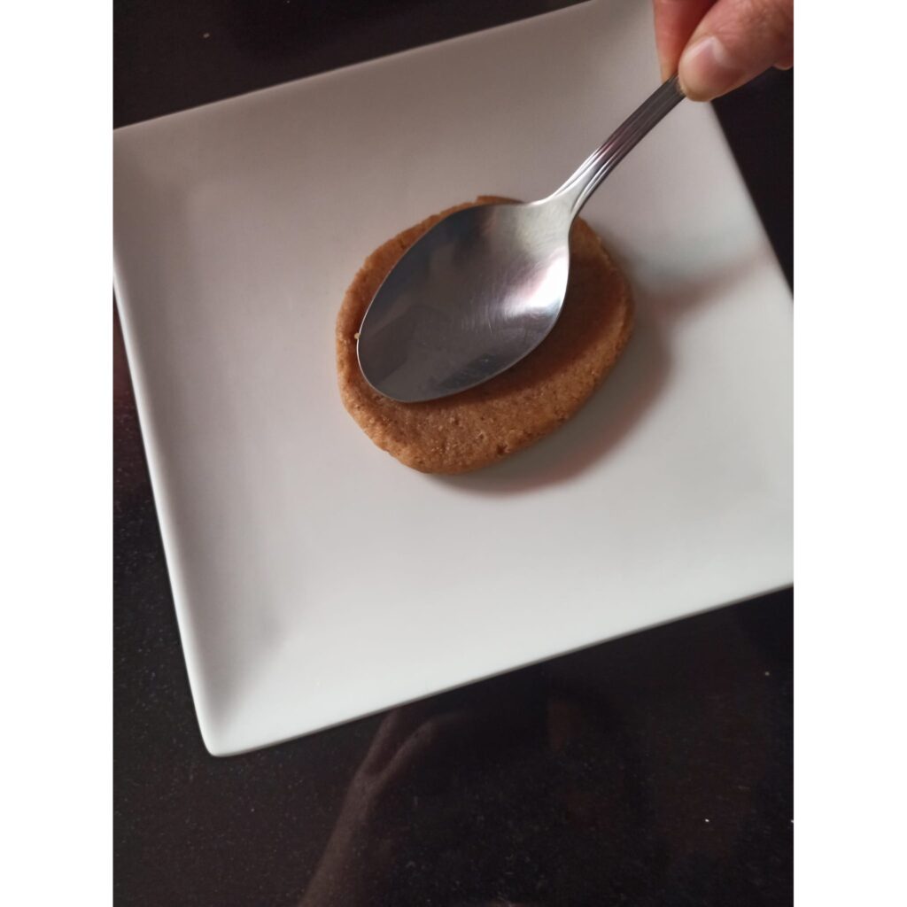 Aplasta las bolas con una cuchara para darles forma y conseguir un grosor de 2 o 3 milímetros. Masa de galletas speculoos aplastadas con una cuchara para darles forma.