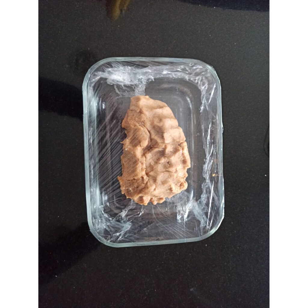 La masa de speculoos debe reposar mínimo una hora en la nevera. Masa de galletas speculoos dentro de un recipiente de cristal y tapada con papel transparente lista para reposar al menos una hora en la nevera.